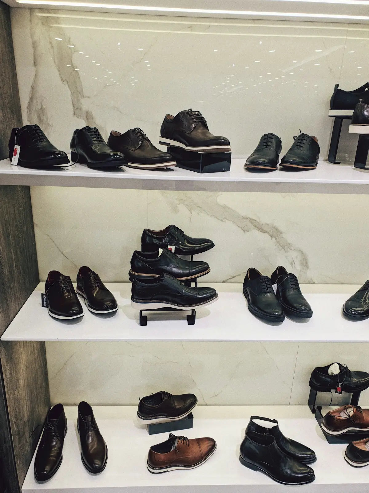 Black leather dress shoes displayed on white shelves.
