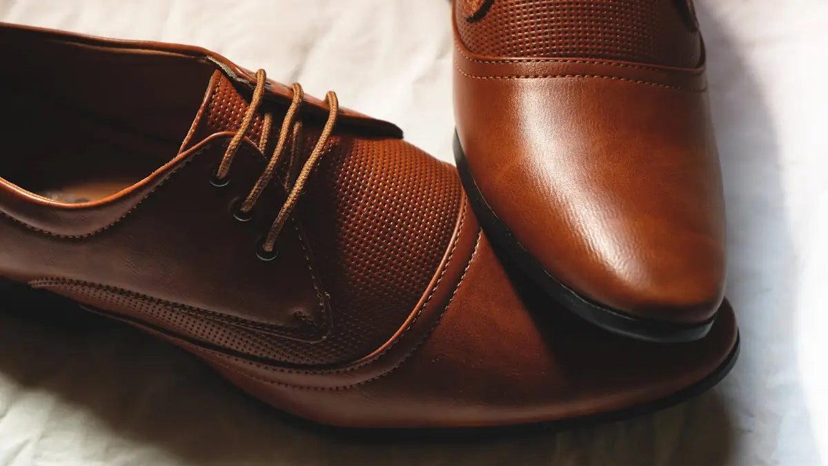 Brown leather dress shoes with a perforated texture on the sides and matching laces.