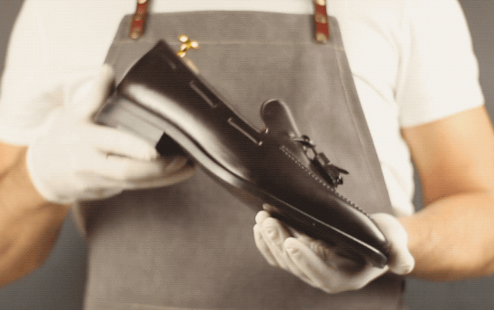 Black leather tassel loafer shoe with a glossy finish and classic design.
