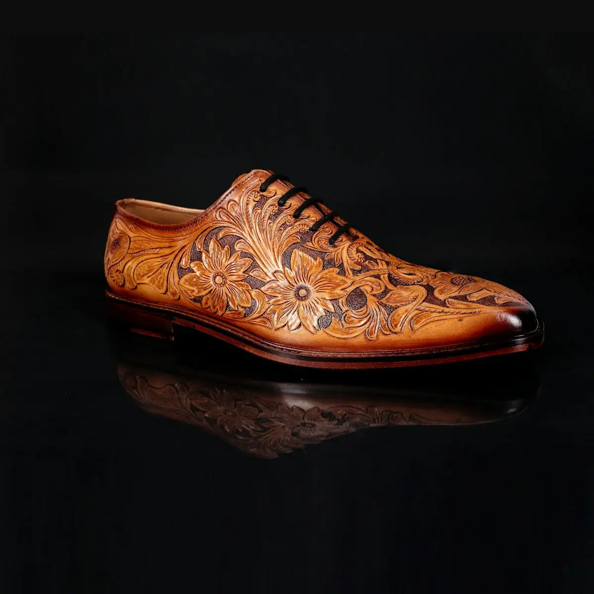 A rich tan leather oxford shoe featuring intricate floral tooled patterns across the upper.