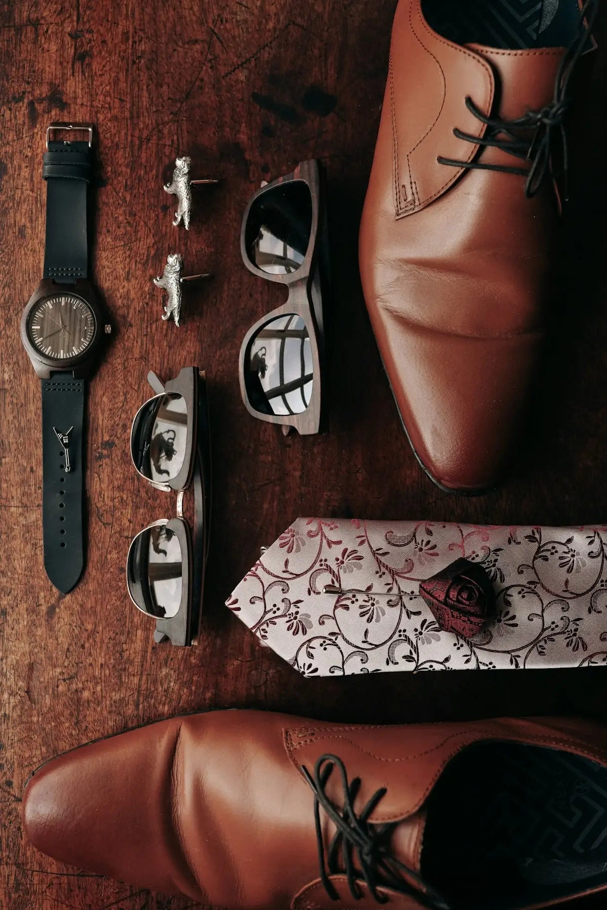 Brown leather dress shoes with laces and floral patterned tie.