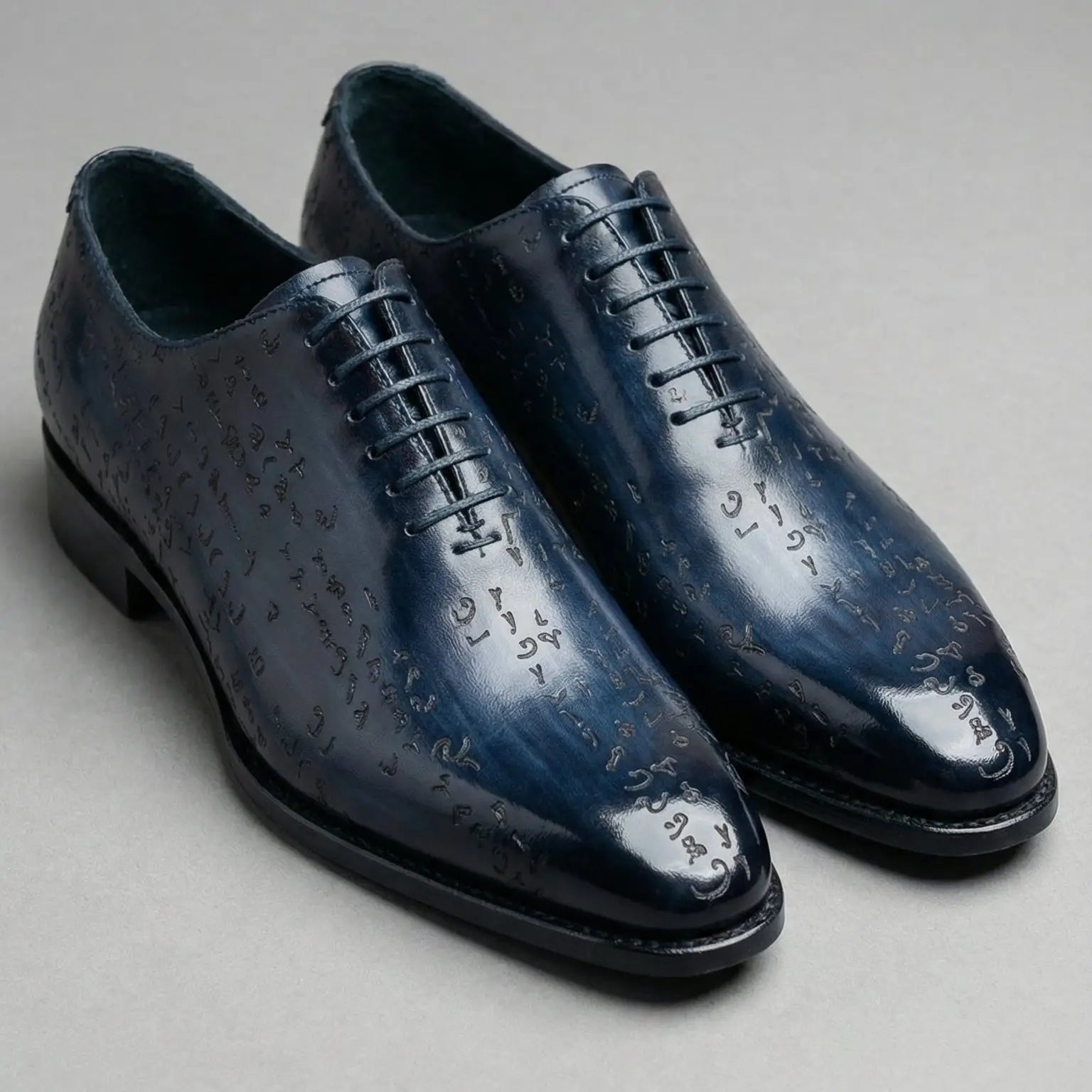 Dark blue leather oxford shoes with an embossed script design across the surface.