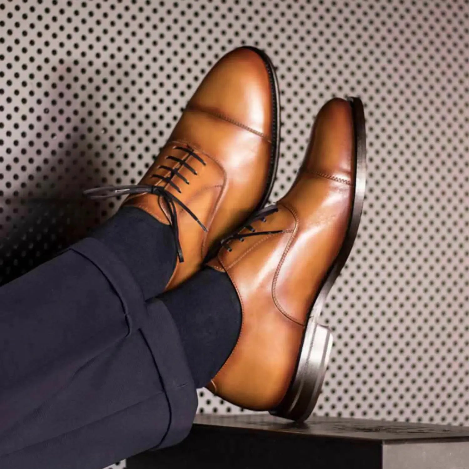 Brown leather cap-toe dress shoes with black laces.
