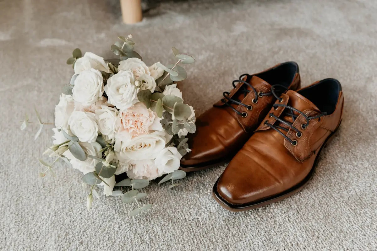 A pair of brown leather dress shoes with black laces and a classic oxford design.