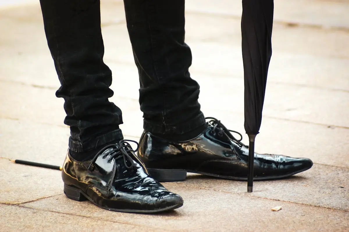 Black crocodile skin oxford shoes with gold accents and patent leather details.