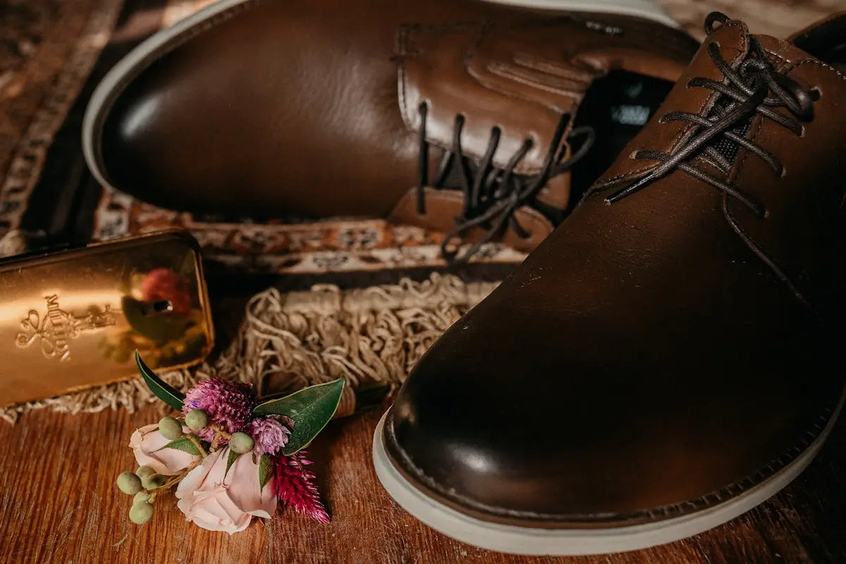 Brown leather lace-up oxford shoes with a classic design and subtle floral boutonniere.