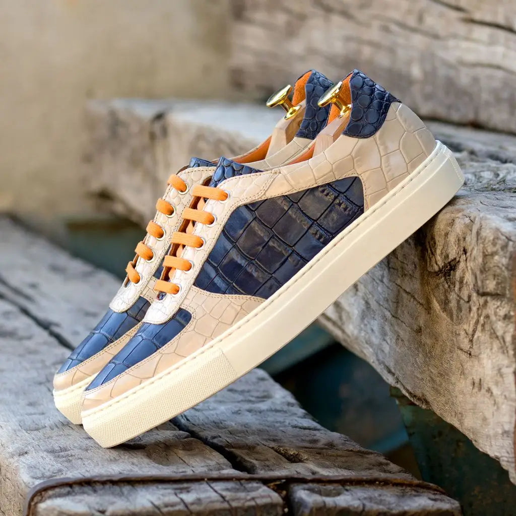 Beige and navy blue croc-embossed leather sneakers with orange laces.