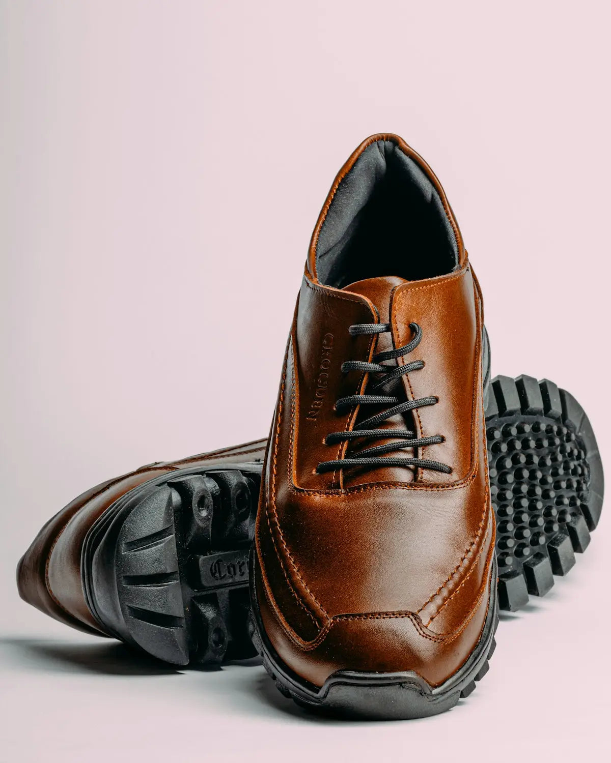 Brown leather lace-up shoes with black laces and a rugged rubber sole.