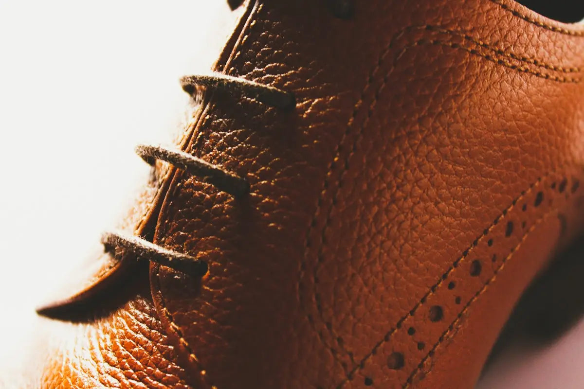 Brown leather brogue shoe with laces and perforations.