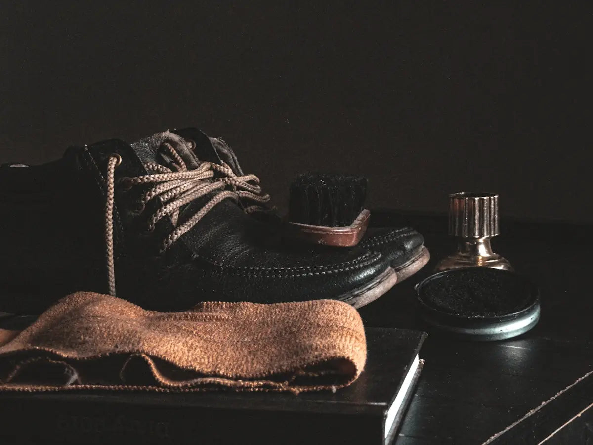 Black leather lace-up shoe with tan laces and visible stitching.